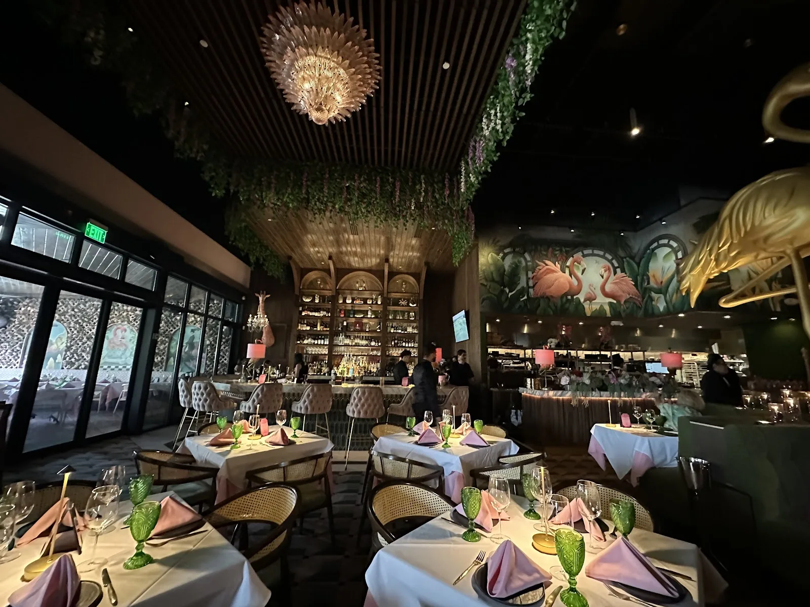 Pink Steak — tropical-jungle dining room with flamingo mural and crystal pendant